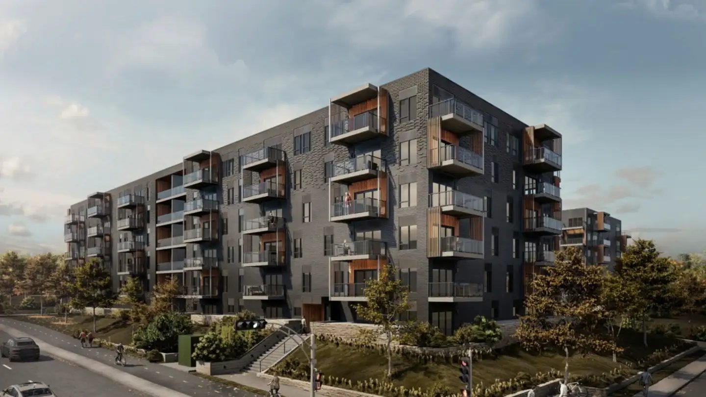 Le Luxenbourg IV, immeuble de condos locatifs de six étages en brique grise avec balcons de bois, sous un ciel de fin de journée à Québec