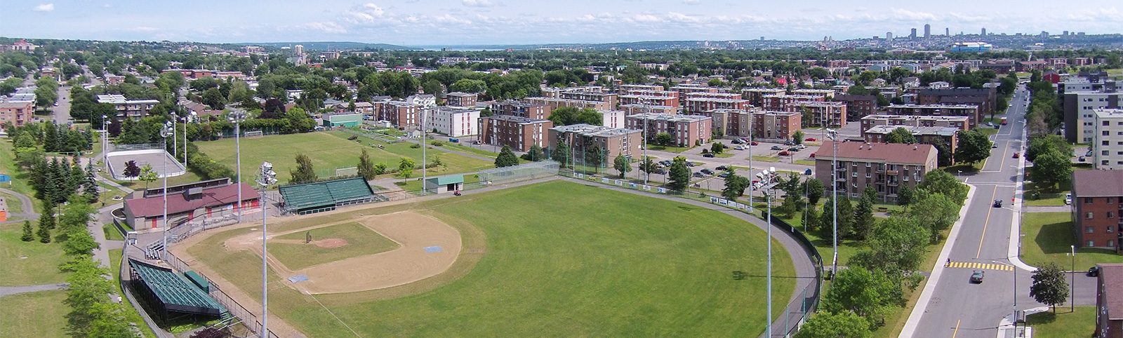 Charlesbourg vu des airs : terrain de baseball, immeubles de brique et la ville de Québec à l'horizon